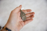 Aged patina and unique textured surface of the vintage African bronze hut pendant.
