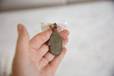 Vintage African bronze spotted hut pendant held in hand, showcasing its aged patina.