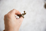Vintage African bronze elephant pendant held in hand to demonstrate its scale.