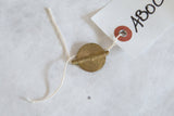Vintage Baule bead collectible, a brass pendant with string attached to its paper tag.