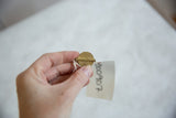 A hand holding a vintage African Baule bead to show its handmade texture and scale.