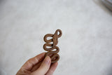 A vintage African iron snake held to show its coiled form and rustic patina.