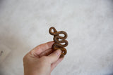 The compact size and rusted texture of a vintage African iron snake held in hand.