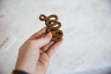 Small African iron snake sculpture held in hand to show scale and rustic texture.