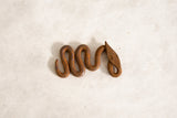 The rustic, coiled form of a handmade vintage African iron snake showing its aged patina.