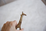 Hand holding vintage African bronze giraffe head and neck, featuring light patina.