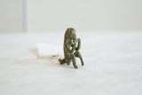 Patinaed bronze monkey figurine with textural details and hand to mouth pose.
