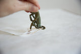 Vintage oxidized bronze monkey figurine held, showing detailed green patina.
