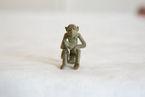 Textured oxidized bronze finish on the vintage African monkey sculpture's body.