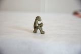 Side profile of a vintage African bronze monkey figurine with patina, holding a banana.