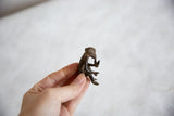 Hand-held vintage African bronze monkey sculpture, showing its side profile.