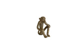 Vintage handmade African bronze sculpture of a sitting monkey eating a banana.