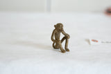 Side profile of a vintage bronze sitting monkey, showing its slender form and handmade texture.