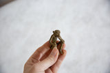 Hand holding the small African bronze monkey, showing its handmade texture and scale.