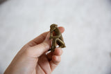 Side profile of the small, handmade bronze monkey showing its aged texture.