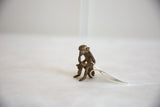 Angled view of the small, handmade African bronze monkey in a seated posture.