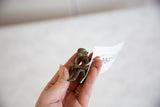 Vintage bronze monkey sculpture held in hand to demonstrate its small, collectible size.