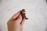 Small vintage African bronze monkey holding banana, showcasing handmade texture.