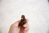 Hand holding small vintage African bronze monkey sculpture with aged patina, holding banana.