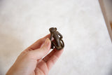 Small vintage African monkey sculpture with aged bronze patina, held in a hand.