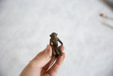 Hand holding the small vintage African bronze sitting monkey, highlighting its textured finish.