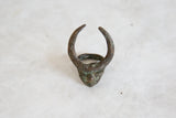 Horned mask face of vintage African bronze ring with visible green patina.