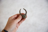 Vintage African bronze horned mask ring with textured surface and mid-century green patina.