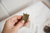 Textured details and aged patina of a cast bronze African shield ring held in hand.