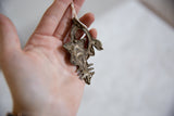 The unfinished back of a vintage African bronze pendant, revealing its raw, handmade texture.