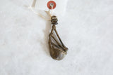 The sculptural form and aged patina of a handmade African bronze instrument pendant.