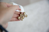 Vintage bronze clover pendant held to show its scale and handmade texture.