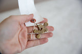 Vintage African bronze clover pendant held in hand to show scale.