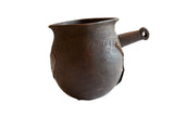 Antique African wooden pitcher with hand-carved details, a side handle, and a dark, rustic patina.