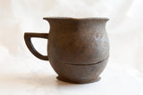Side profile of the antique wooden pitcher showing its handle and aged crack.