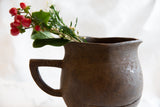 Angled view of the antique African pitcher's rustic handle and textured surface.