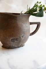 Side view of the antique African pitcher highlighting its rustic, repaired surface.