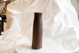 The tall antique African vase's aged wood finish, showing character-rich cracks on the rim.