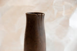Age-related cracks and rich patina on the rim of an antique wooden vase.