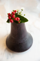 Antique African wooden vase with carved geometric bands, red berries, and white flowers.