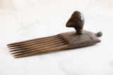 Hand-carved texture and rich patina on an antique African wooden bird comb.
