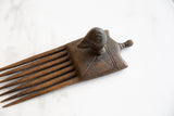 Detail of the hand-carved patterns and dark wood texture on the African bird comb.