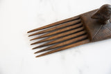 Hand-carved dark wood teeth and textured handle of the antique African comb.
