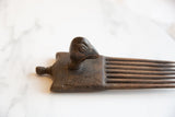 African wooden comb, showing dark, aged wood with carved bird head and prongs.