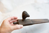 Hand holding the antique African wooden bird comb, showing aged wood and comb teeth.