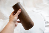 Aged dark brown wood texture and rounded bottom of an antique African vase.