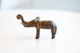 Vintage African bronze elephant sculpture in profile, with a curled trunk and aged patina.