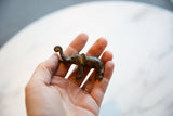 Angled view of handmade vintage African bronze elephant, with curled trunk and aged patina.
