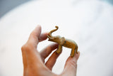 Vintage African handmade bronze elephant figurine with trunk raised, golden patina.