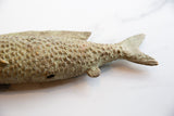 Textured scales and sculpted tail fin on a vintage bronze fish with patina.