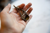 Small vintage African bronze instrument held in hand, showing its handmade texture and scale.